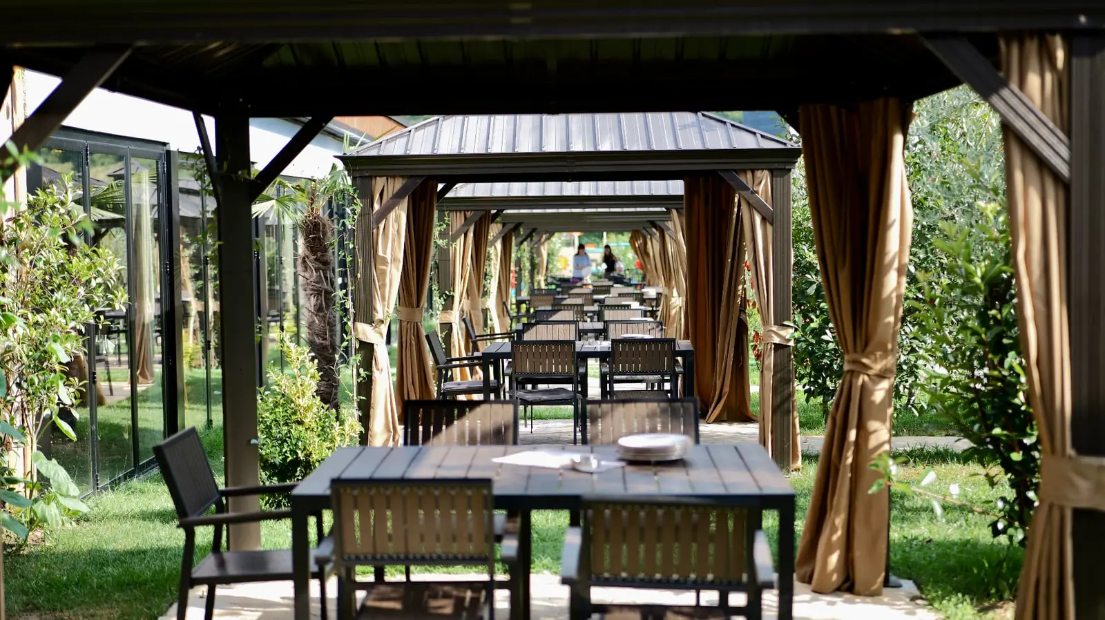 Row of curtained gazebos with set tables in the garden at OKO Farm