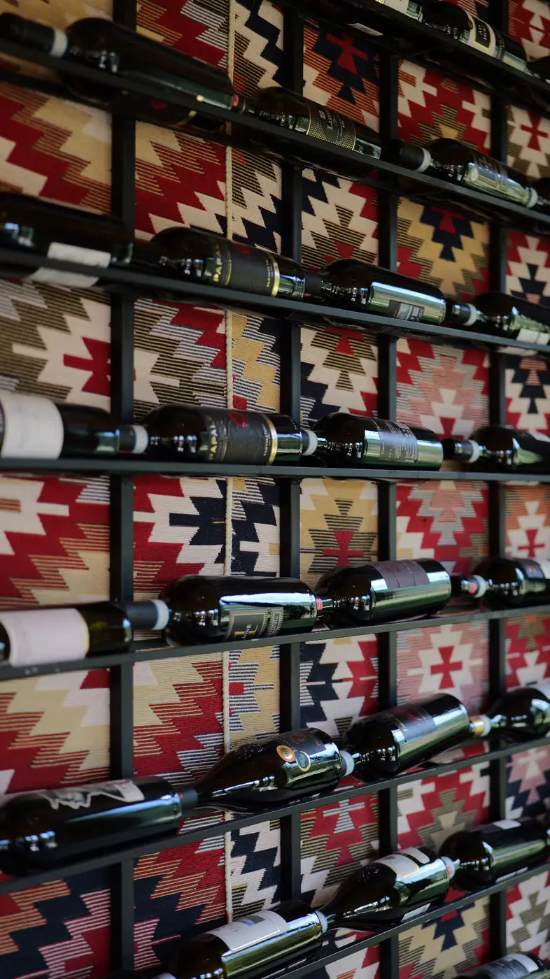 Wine bottle wall backed with a traditional Albanian kilim pattern