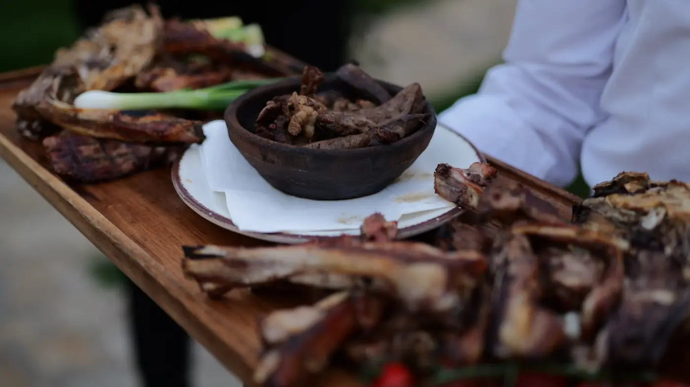 Wooden board of grilled meats, ribs and spring onions carried to the table