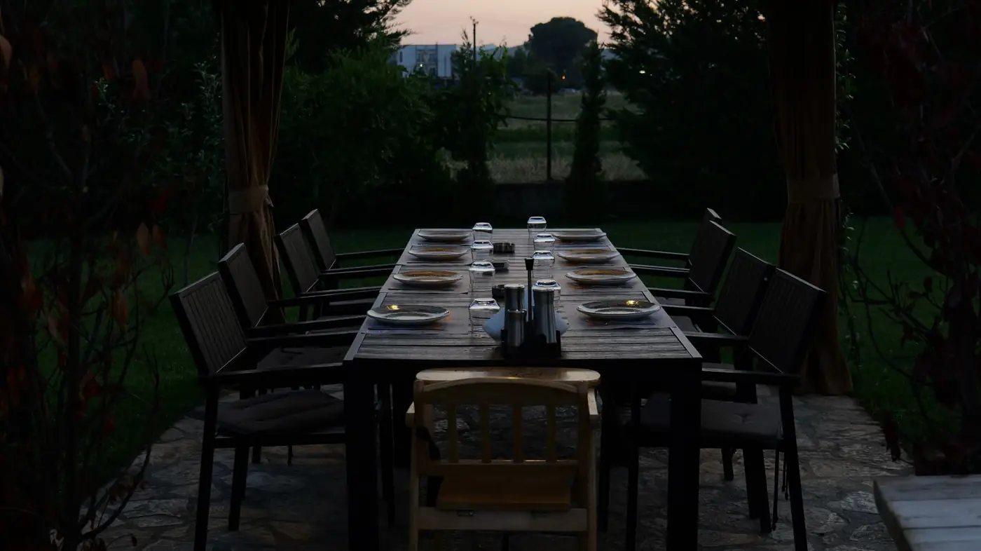 Long gazebo table set for eight with the sunset over the fields behind