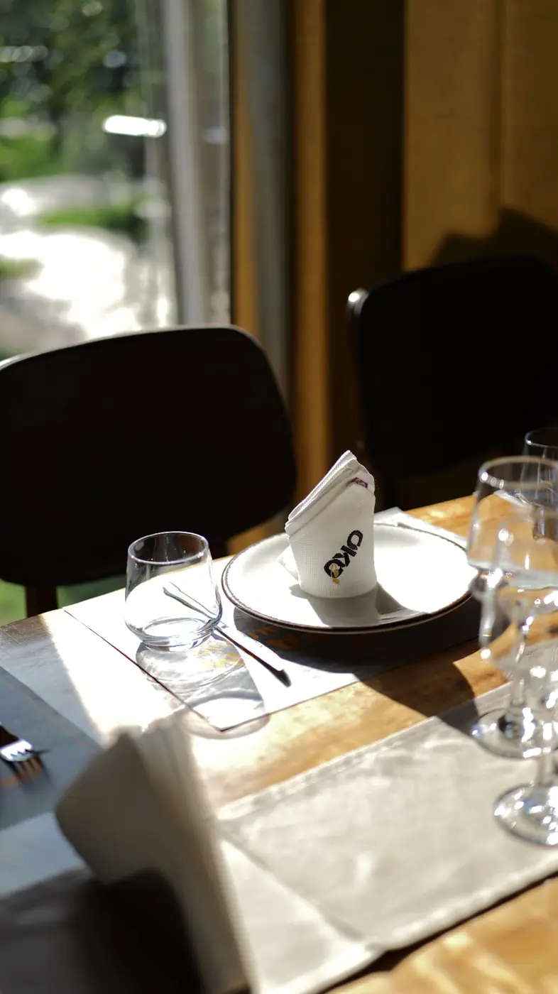 Table set with an OKO branded napkin, plate and glasses in the sunlight