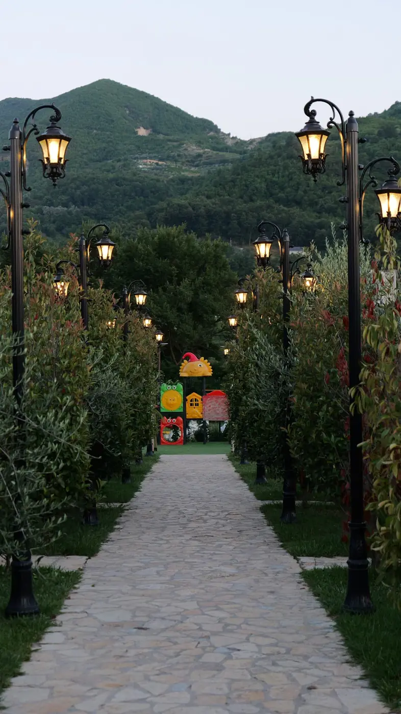 Stone path lined with lamp posts through the garden of OKO Farm at dusk