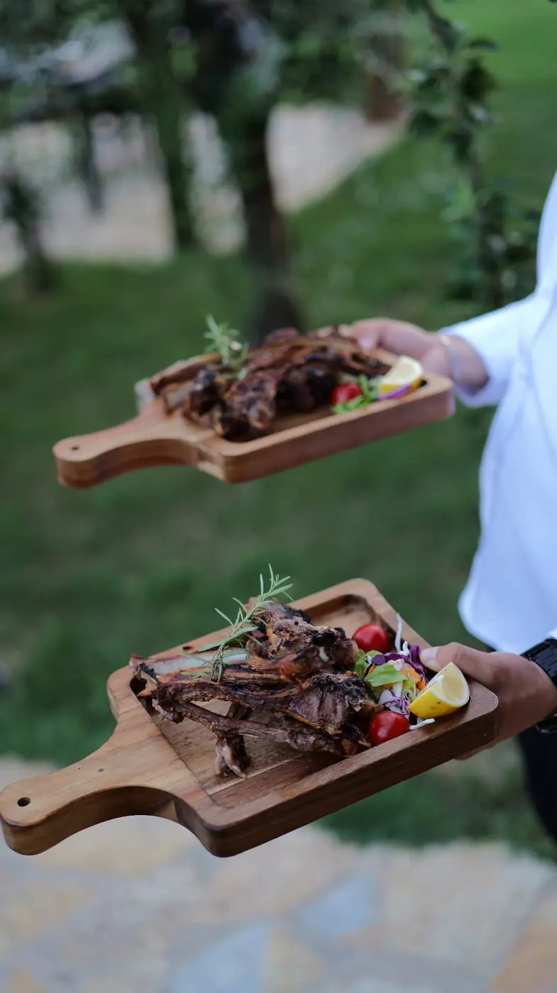 Two wooden boards of grilled lamb chops served in the garden