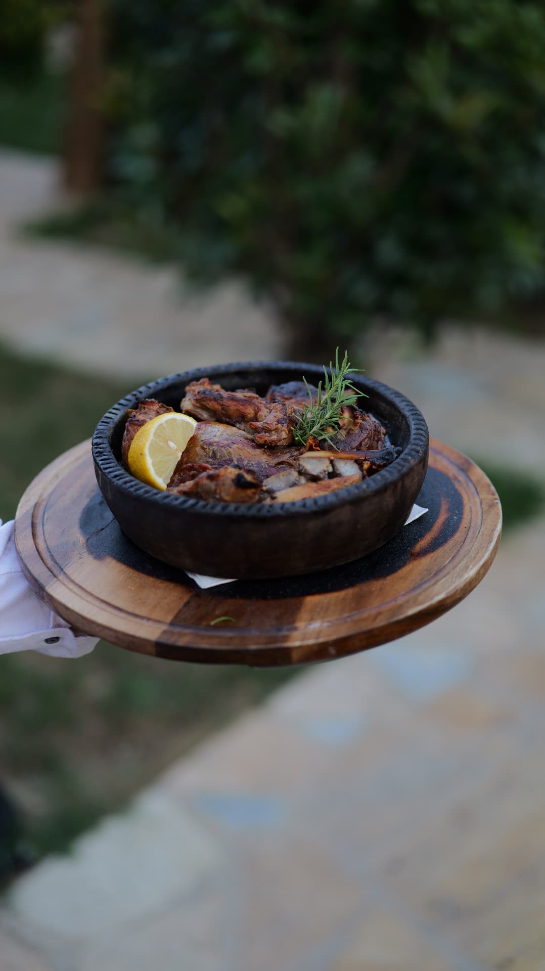 Braised lamb with rosemary and lemon served in a clay pot on a wooden board